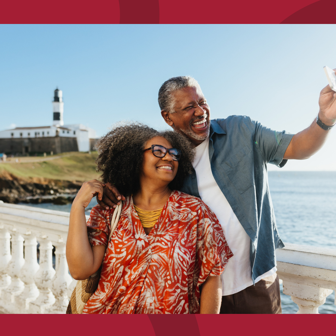 A couple taking a selfie with a lighthouse in the background.